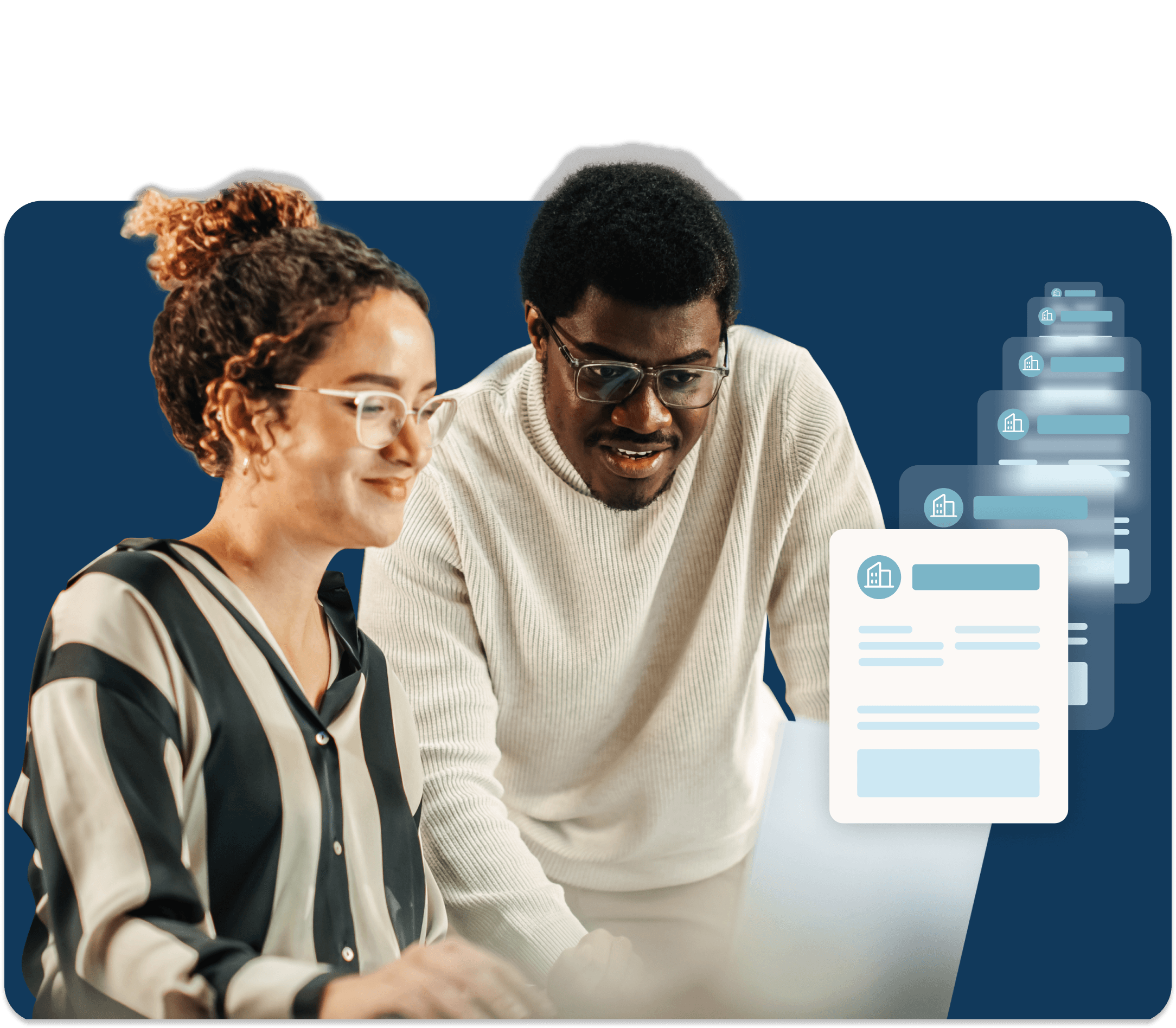 Two coworkers work together on a laptop while transferring documents.