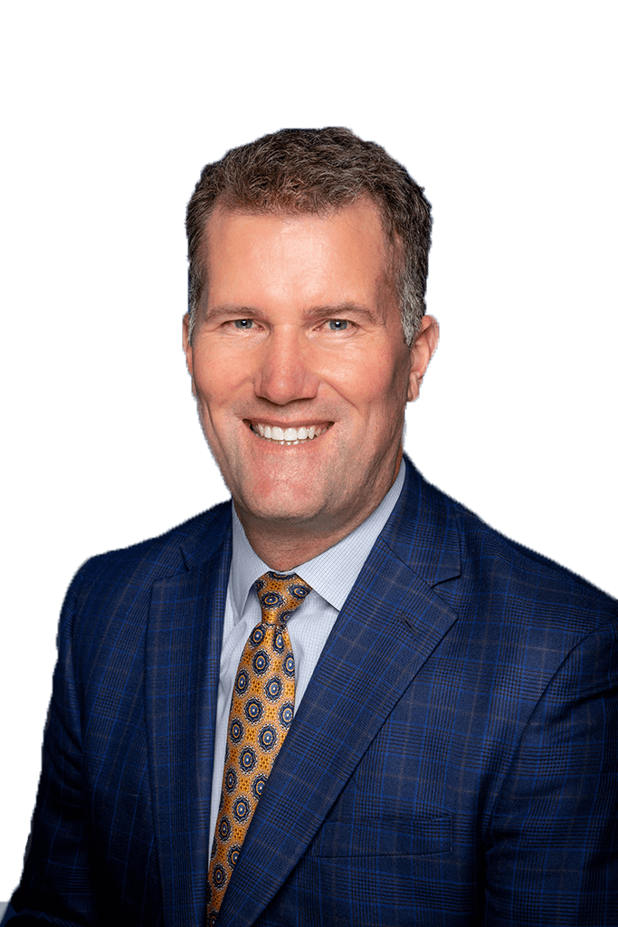 A man in a dark navy linen jacket with a yellow a blue polka dotted tie smiles at the camera.